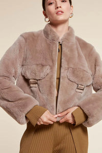 Short real  fur jacket with small collar and drawstring hem. Zip fastening. Chest pockets with a flap and buckle