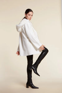 White parka with fur hood made of cashmere fabric. High collar and detachable fur hood. Kimono sleeves. Zip fastening.